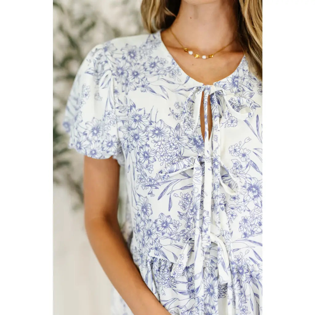 A romantic toile-inspired plus size friendly blouse in ivory and blue with dainty bows a flattering peplum fit. Sweet