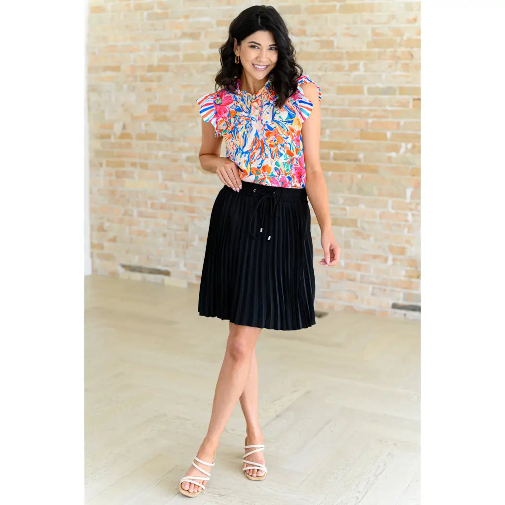 Floral ruffle neck blouse with flutter sleeves and V-keyhole. Polished woven fit offered in sizes SM to 3XL. Ships 2–3