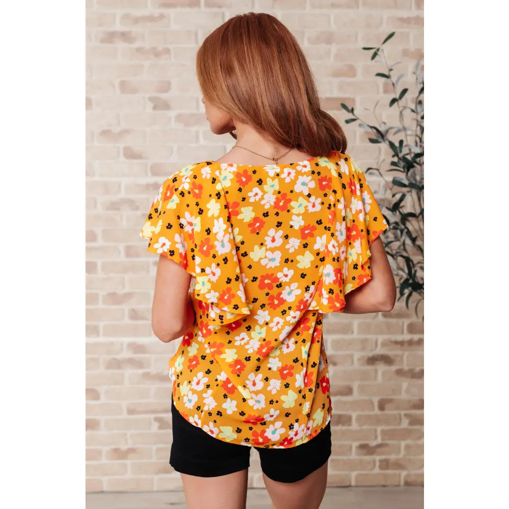 Shop our Freshly Picked Orange Floral Top featuring ruffle cap sleeves & a flattering V-neckline. Plus it’s available