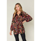 Chic abstract print tunic blouse with flowy fit and ruffled neckline. Sizes SM–3XL. Perfect plus size office top