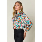Chic abstract print tunic blouse with flowy fit and ruffled neckline. Sizes SM–3XL. Perfect plus size office top