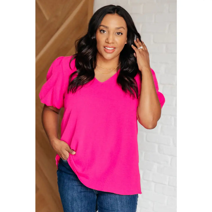 Hot pink puff sleeve blouse with V-neck and flowy fit. Available in standard curvy plus sizes. Lightweight bold &