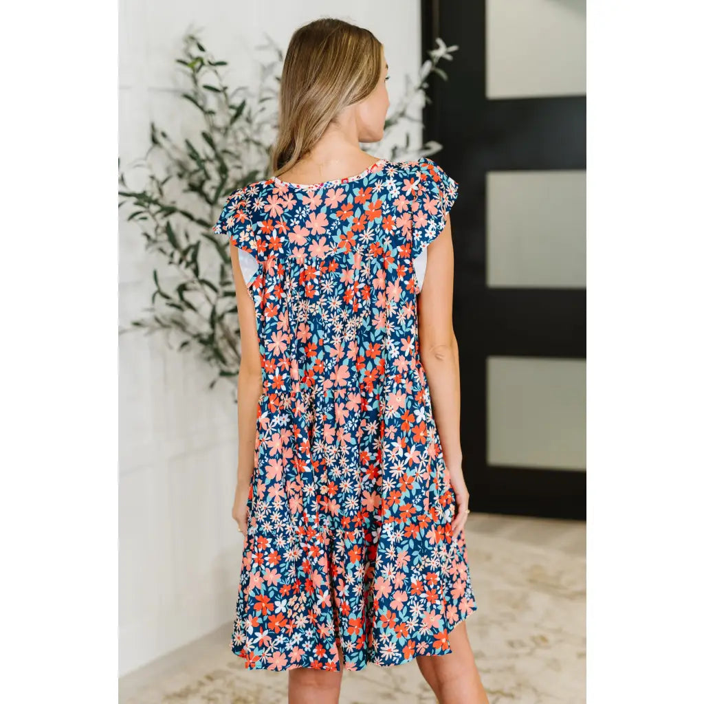 Shop the Pocket of Petals flutter sleeve mini dress in navy and coral. A flattering tiered silhouette with pockets