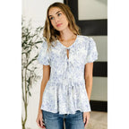 A romantic toile-inspired plus size friendly blouse in ivory and blue with dainty bows a flattering peplum fit. Sweet