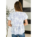 A romantic toile-inspired plus size friendly blouse in ivory and blue with dainty bows a flattering peplum fit. Sweet