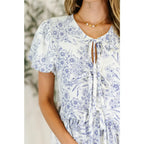 A romantic toile-inspired plus size friendly blouse in ivory and blue with dainty bows a flattering peplum fit. Sweet