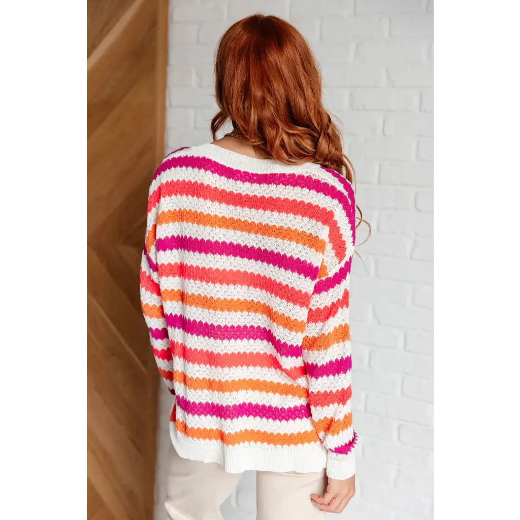 Loose knit striped sweater in coral and magenta. Plus size friendly fit with V-neck side slits. Cozy layering piece