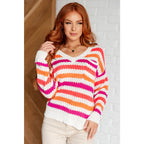 Loose knit striped sweater in coral and magenta. Plus size friendly fit with V-neck side slits. Cozy layering piece