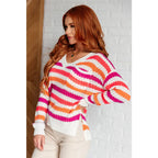 Loose knit striped sweater in coral and magenta. Plus size friendly fit with V-neck side slits. Cozy layering piece