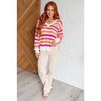 Loose knit striped sweater in coral and magenta. Plus size friendly fit with V-neck side slits. Cozy layering piece