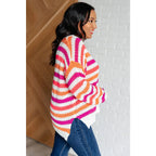 Loose knit striped sweater in coral and magenta. Plus size friendly fit with V-neck side slits. Cozy layering piece