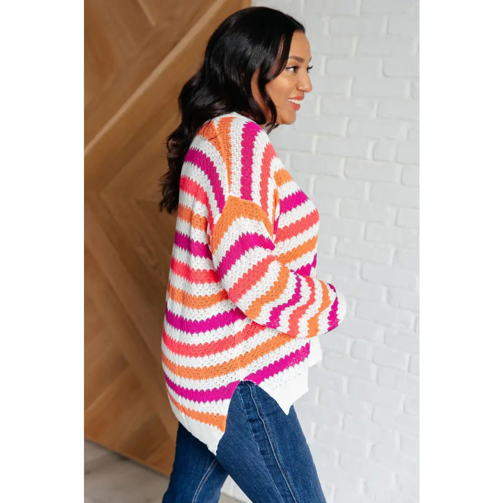Loose knit striped sweater in coral and magenta. Plus size friendly fit with V-neck side slits. Cozy layering piece