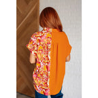 Make a statement in the Two Sides to Story Blouse! Half solid orange half paisley and floral mix print short sleeve top