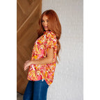 Make a statement in the Two Sides to Story Blouse! Half solid orange half paisley and floral mix print short sleeve top