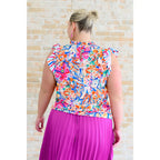 Floral ruffle neck blouse with flutter sleeves and V-keyhole. Polished woven fit offered in sizes SM to 3XL. Ships 2–3